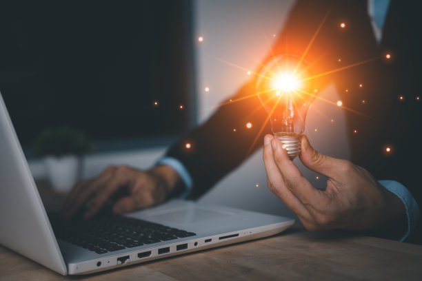 商人手持虚拟灯泡与笔记本(笔记本)。新思路、新灵感和创新技术理念。科学与传播理念。图片下载