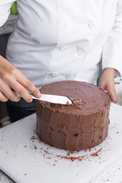 用刀在巧克力蛋糕上点缀可可奶油，美味的甜点图片下载