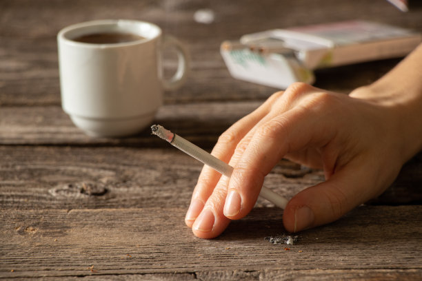 姑娘手里一根烟，桌子上挨着一杯咖啡，香烟和咖啡，习惯不好图片下载