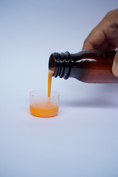 女手将止咳糖浆倒入白底量杯中。健康的概念图片下载