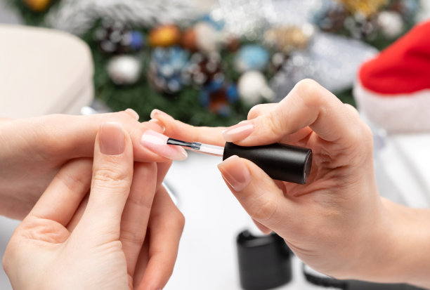 美甲师在美容院给指甲涂上啫喱油。专业护理手。新年的概念。图片下载
