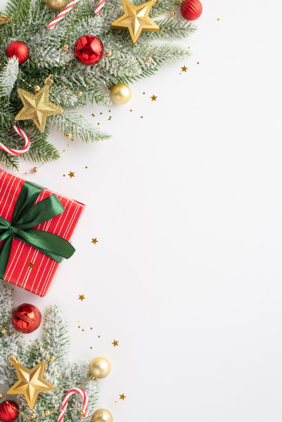 圣诞节的概念。顶视图垂直照片礼品盒弓松枝在雪装饰红色的小饰物，金星饰品糖果拐杖和纸屑在孤立的白色背景与copyspace图片下载