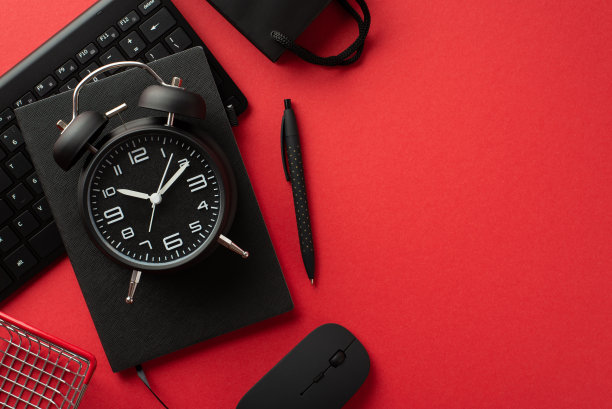 “黑色星期五”的概念。顶视图照片黑色闹钟计划笔纸袋购物车电脑鼠标和键盘孤立的红色背景图片下载