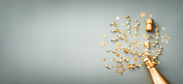 金色的香槟酒瓶上有五彩纸屑的星星和蓝色背景上的派对装饰。圣诞、生日或新年卡片。图片下载