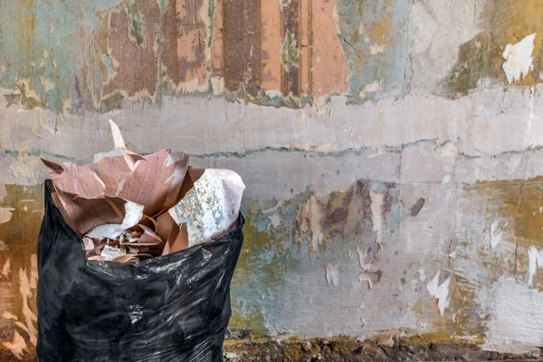 黑色垃圾袋与旧纸墙纸的背景上一个模糊的剥落褪色的墙图片下载