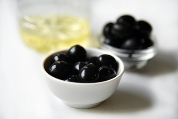 炖锅里放黑橄榄，白色底色上放橄榄油。图片下载