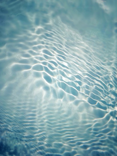 离焦模糊透明蓝色清澈平静的水面纹理与飞溅和气泡。新潮抽象的自然背景。阳光下的水波与复制空间。蓝色水彩闪亮的图片下载