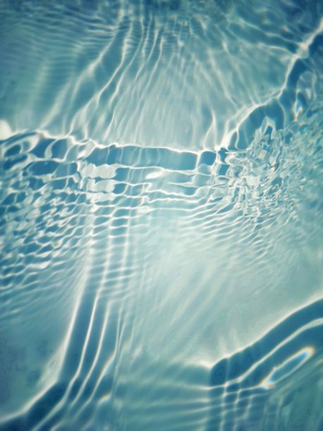 离焦模糊透明蓝色清澈平静的水面纹理与飞溅和气泡。新潮抽象的自然背景。阳光下的水波与复制空间。蓝色水彩闪亮的图片下载