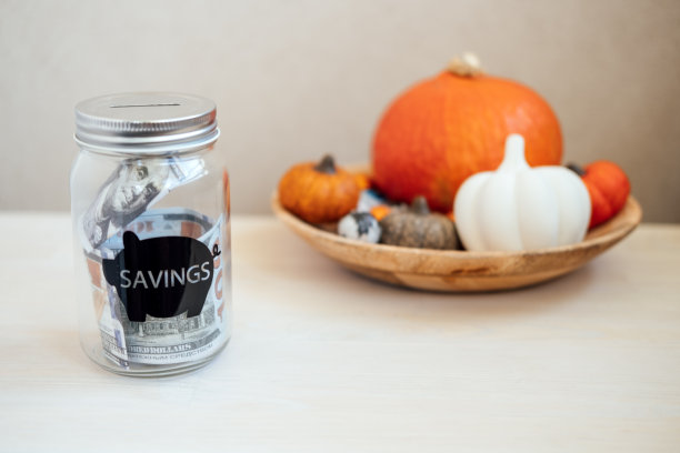 感恩节的想法，节约，预算中的感恩节。玻璃梅森罐扑满与美元现金感恩节南瓜装饰背景图片下载