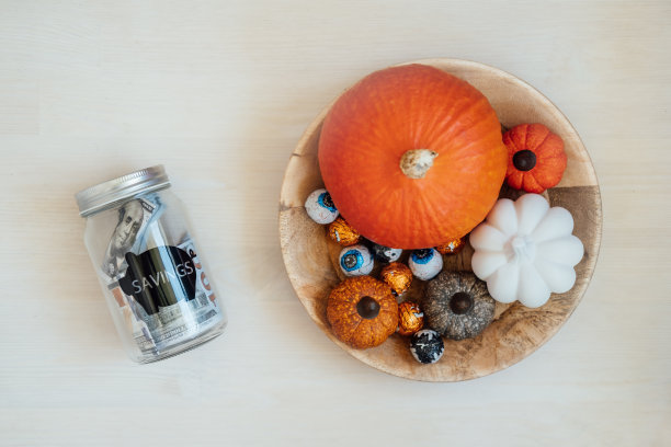 万圣节省钱，省钱，万圣节有预算。玻璃梅森罐扑满美元现金万圣节南瓜装饰背景图片下载