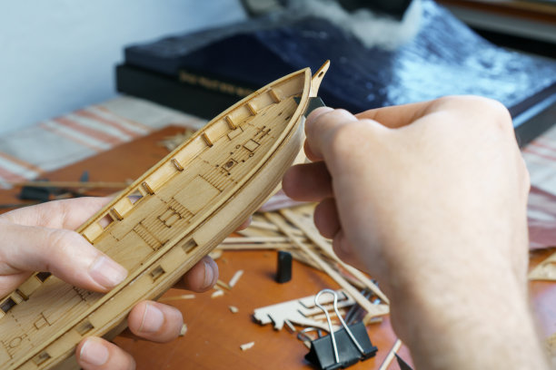 手工用文书刀从胶合板上切割出船模的细节。制作玩具船工艺，工艺品。图片下载