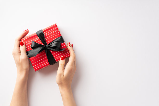 “黑色星期五”的概念。第一人称俯视图照片的年轻女性双手演示红色礼盒与蝴蝶结孤立的白色背景与copyspace图片下载