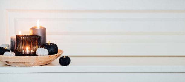 横幅黑色白色最小南瓜蜡烛组成万圣节和感恩节。节日的秋天组成画黑色金色的南瓜和燃烧的黑色蜡烛在家庭内部。图片下载