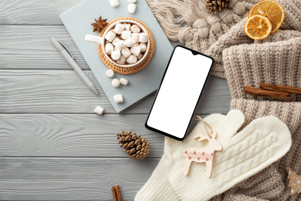 俯视图照片杯可可棉花糖在藤垫智能手机日记笔鹿饰品手套格子松果肉桂棒和干橙片在灰色木桌背景图片下载