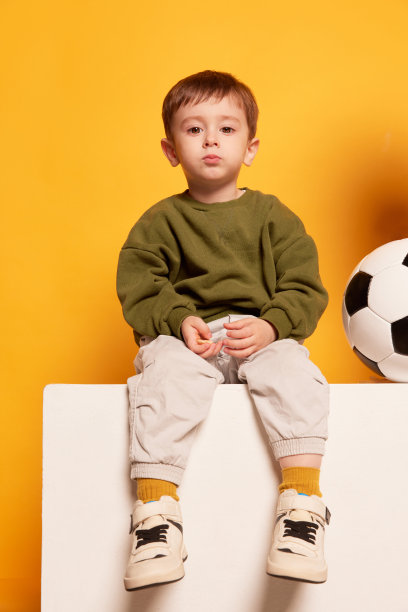 迷人可爱的小男孩坐在大盒子上，看着相机。情感，儿童时尚，快乐童年理念图片下载