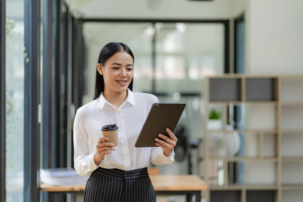 微笑的女执行经理提供专业的商务服务，手持平板电脑站在办公室图片下载