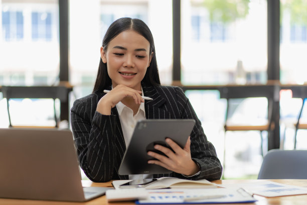 一名亚洲女商人用笔、笔记本电脑和计算器指着图表分析一份报告。在工作站会计电话营销的概念，电子商务，免费在线营销。图片下载