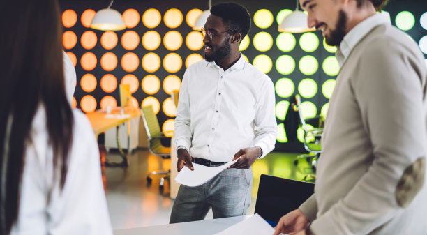 黑色开朗的男员工与同事在办公室工作图片下载