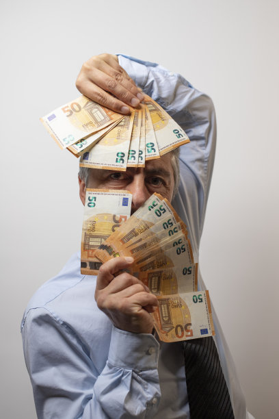 50岁的富商在玩一叠钞票。利润、资本主义和富裕的概念图片下载