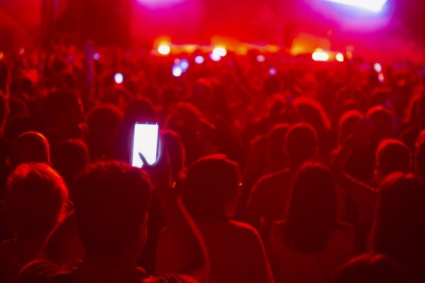 人们在音乐会上使用手机。手拿手机。音乐会现场的观众用手机拍照。图片下载