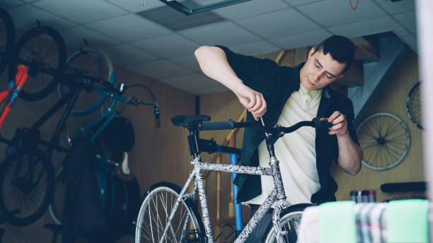 熟练技工在车间内使用专业工具和配套配件固定现代自行车车把。自行车保养和人的观念。图片下载