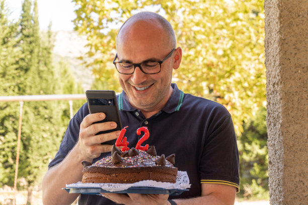 微笑的男人手持手机录制生日蛋糕图片下载