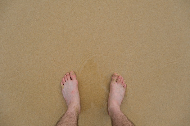 下，沙滩上黄沙上的人脚的视角图片下载