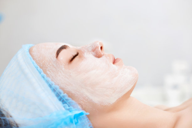 美丽的女人与蓝色藻酸盐面膜在脸上图片下载