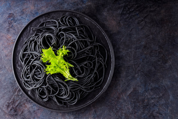 黑底墨鱼墨汁的黑色意大利面。煮过的黑色意大利面和绿莴苣。前视图。本空间图片下载