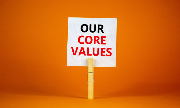 我们的核心价值象征。白纸上写着“我们的核心价值观”，夹在木衣夹上。美丽的橙色背景。业务和我们的核心价值理念。副本的空间。图片下载
