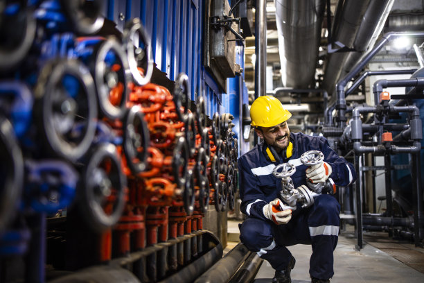工业维修服务，有经验的工程师在炼油厂更换管道阀门。图片下载