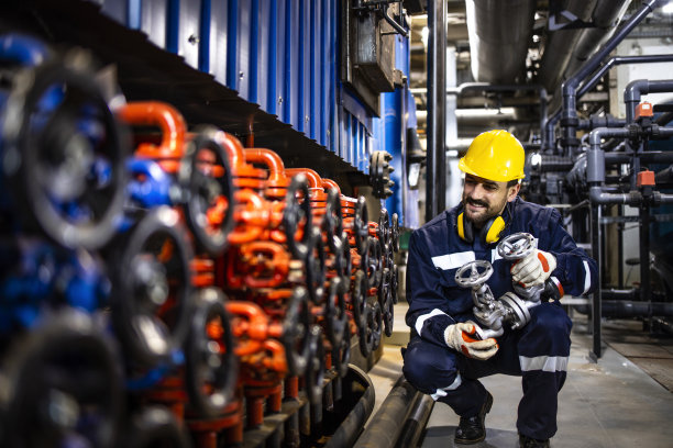 供热工厂工人更换工业管道阀门作为定期维护程序。图片下载