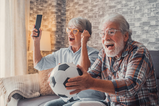 一对快乐的学长或足球迷在电视上观看足球比赛，在家里庆祝胜利。家庭、体育、娱乐理念。图片下载