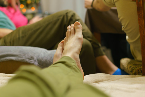 一个人的脚翘在马车上，背景里有其他人。绿色或卡其色裤子。亲密感。享受。优雅。健康。指甲。手指。枕头。的生活。男孩。男性。青年。的儿子。指甲图片下载