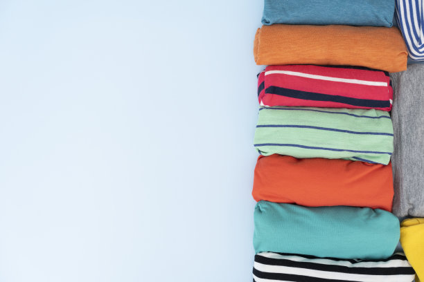 特写卷彩色t恤衣服上蓝色的桌子背景，旅行的概念图片下载