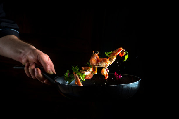 厨师在锅里和蔬菜一起煮虾。烹饪海鲜、健康素食和深色背景的食物。冻结。免费的广告空间图片下载