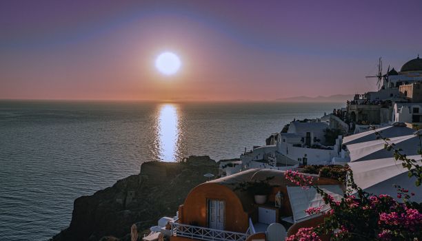 在希腊圣托里尼岛，日落时太阳反射在海里的风景照片图片下载
