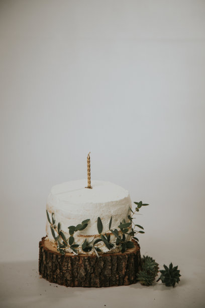 垂直拍摄的奶油蛋糕在一个切割树干与燃烧的蜡烛在白色的背景图片下载