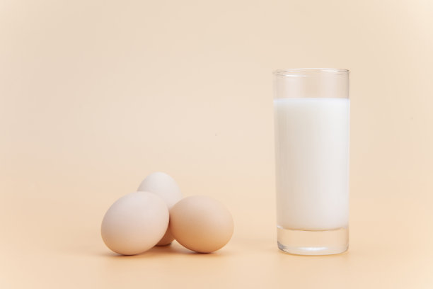 一杯牛奶和一些鸡蛋放在橙色的表面上图片下载