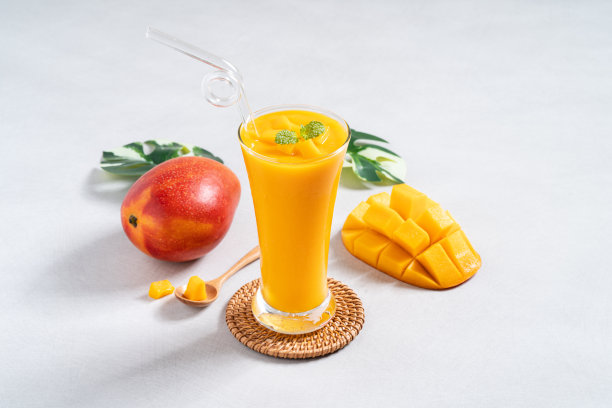 新鲜美丽美味的芒果果汁冰沙在灰色的桌子背景上的玻璃杯。图片下载