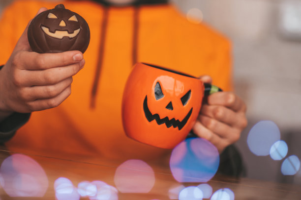 偷拍真实变焦男孩的肖像与杯茶和糖果在家里万圣节派对图片下载