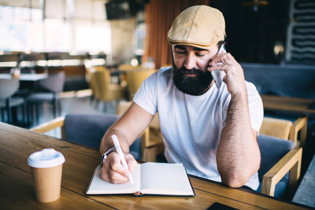 专心的男人打电话，用记事本写东西图片下载