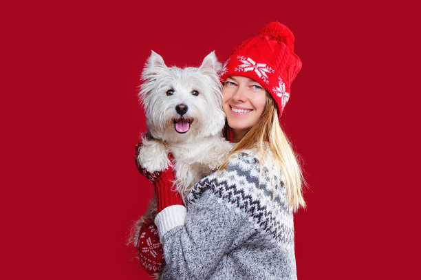 戴着帽子和手套的白人妇女，手里拿着狗图片下载