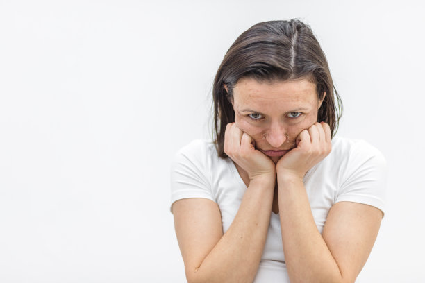 皮肤干燥的妇女在白色背景上触摸她的脸的照片。图片下载