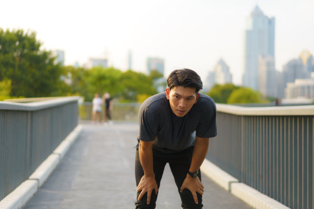 亚洲疲惫男子在一次极限运动活动后筋疲力尽，晚上在城市公园跑步图片下载