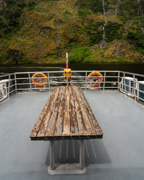 在新西兰峡湾可疑湾的河中，船上的旧木桌图片下载