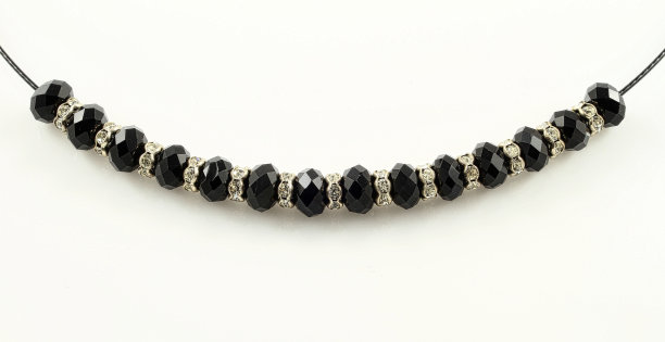 特写镜头的手镯与黑色闪亮的珠子孤立在一个白色的背景在工作室图片下载