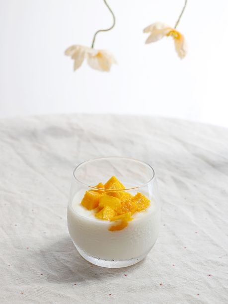 在白色背景上，美味的芒果片和一杯奶昔的垂直特写镜头图片下载