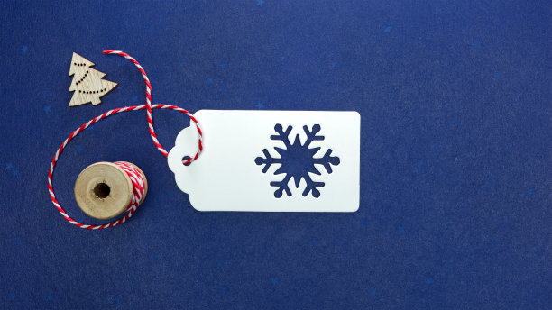 礼品标签与红白绳索和蓝色背景上的小玩意。圣诞节的概念。图片下载