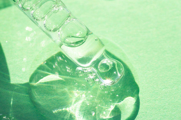 移液管与透明化妆品液体或面部精华液在绿色背景。用于皮肤护理的水化物或化妆品油的质地。有选择性的重点图片下载